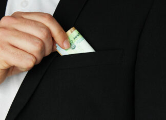 Ростовская область заняла третье место по коррупции в России Мужчина прячет деньги в карман //Фото Freepik, wirestock
